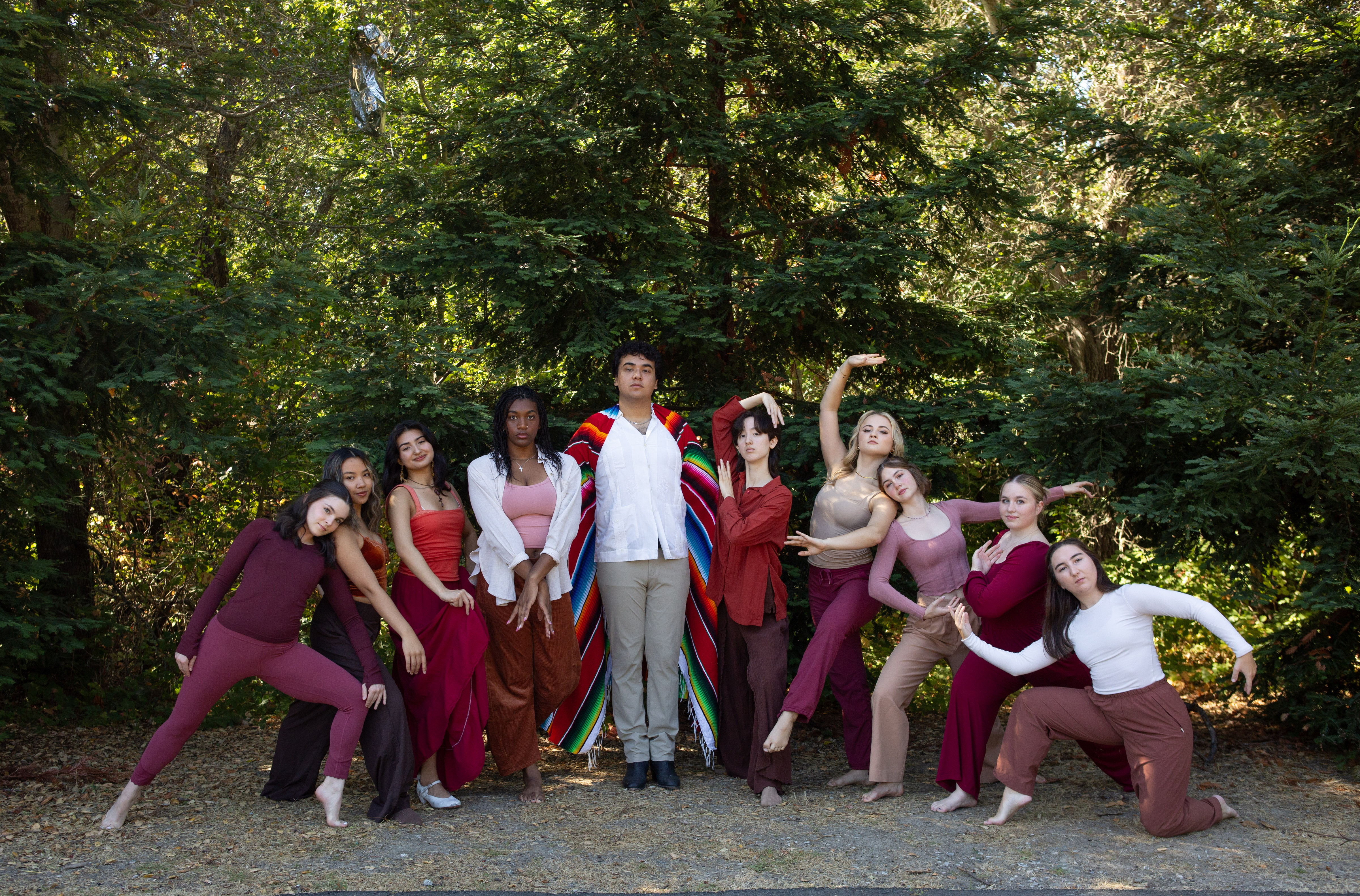 Senior SMC dancers posing in front of a forest of trees with maroon accessories and clothing.