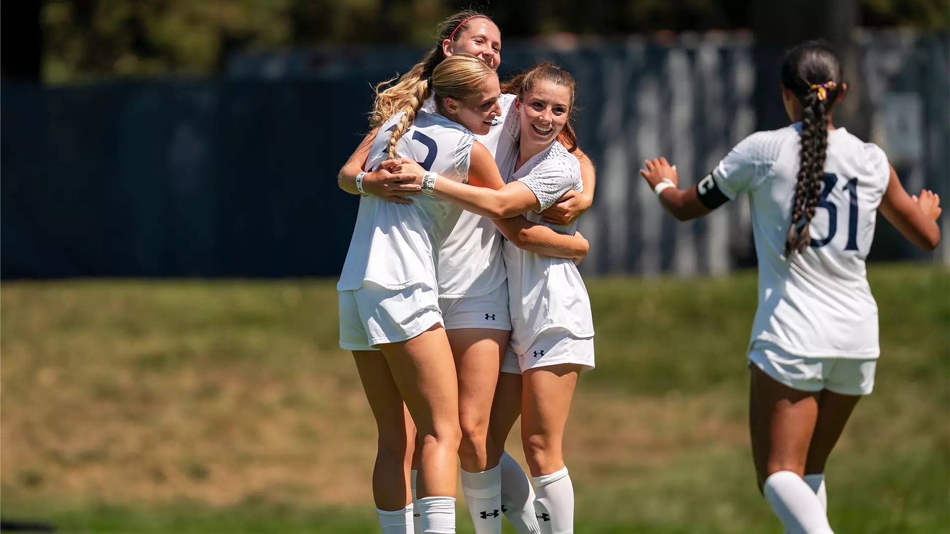 Four women's soccer players celebrate a victory in fall 2025