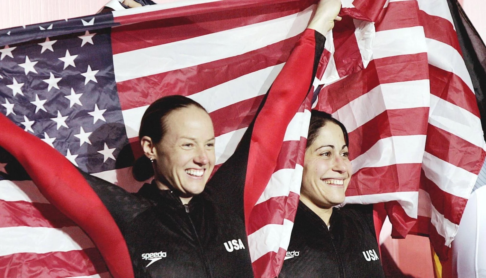 Shauna Rohbock and Valerie Fleming holding an American flag after winning an Olympic medal