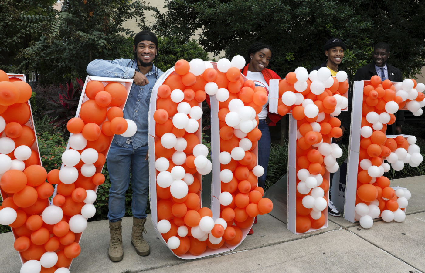 students standing behind the each letter of 'Vote' that is decorated in balloons