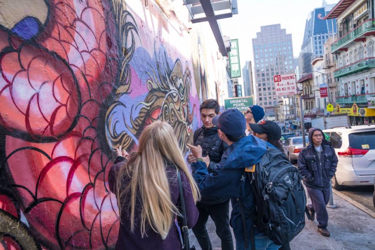 group of people standing next to and talking about a mural