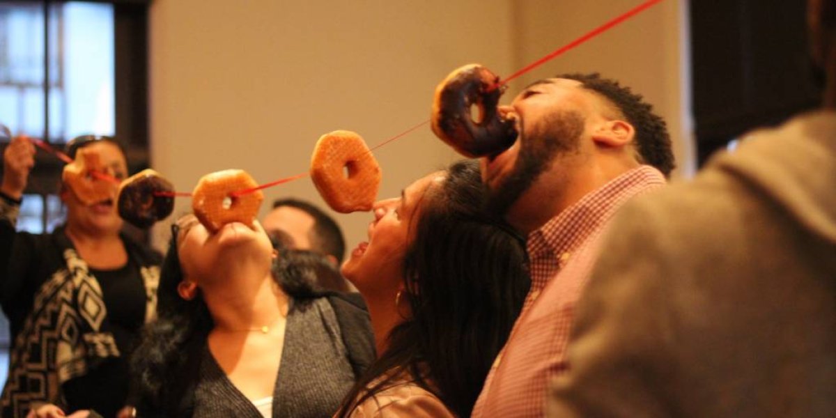 people eating donuts hung from the ceiling by a string