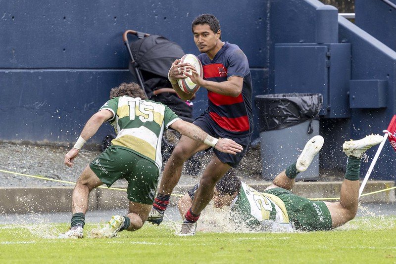 Saint Mary's player Aisake Tukuafu '28 avoids one Colorado State defender and attempts to evade another Colorado State defender as the wet field splashes while the players try to keep their footing. 