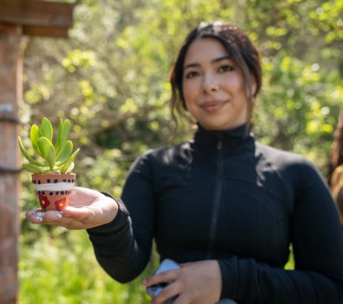 Student holding a succulent in a pot at 2024 Earth Day Crafternoon