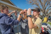 Three male students helping assemble housewares as part of a service project for hurricane relief in 2020