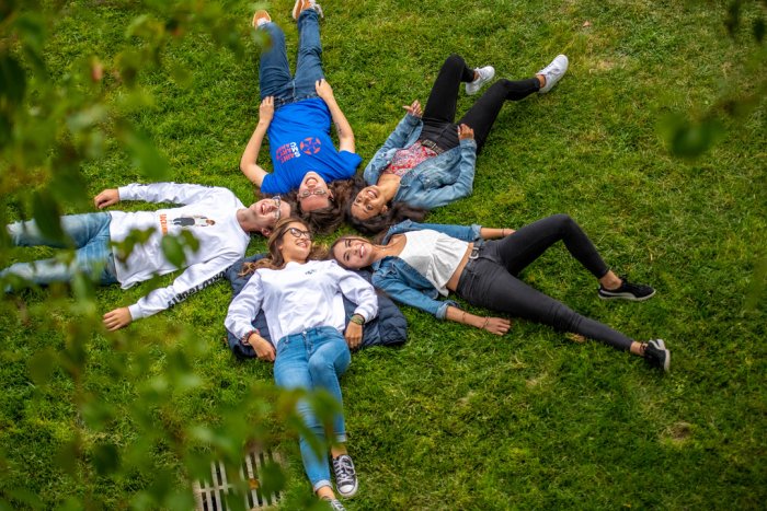 Students laying on the grass with their heads together in a star shape