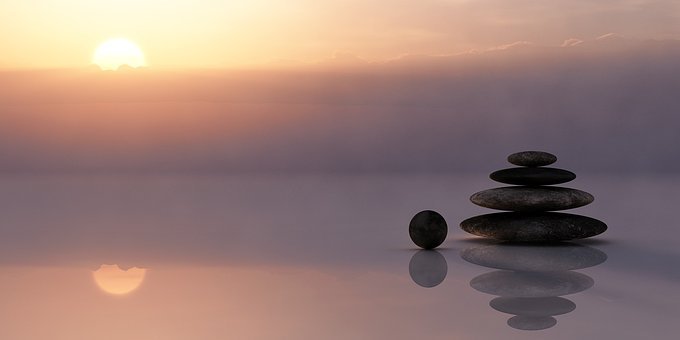 Picture of rocks stacked near water with sunrise in background
