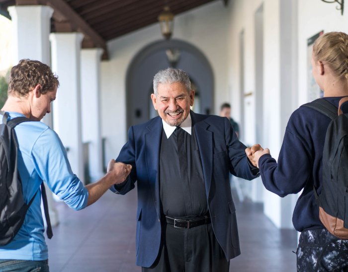 Brother Camillus Chavez fistbumping two students