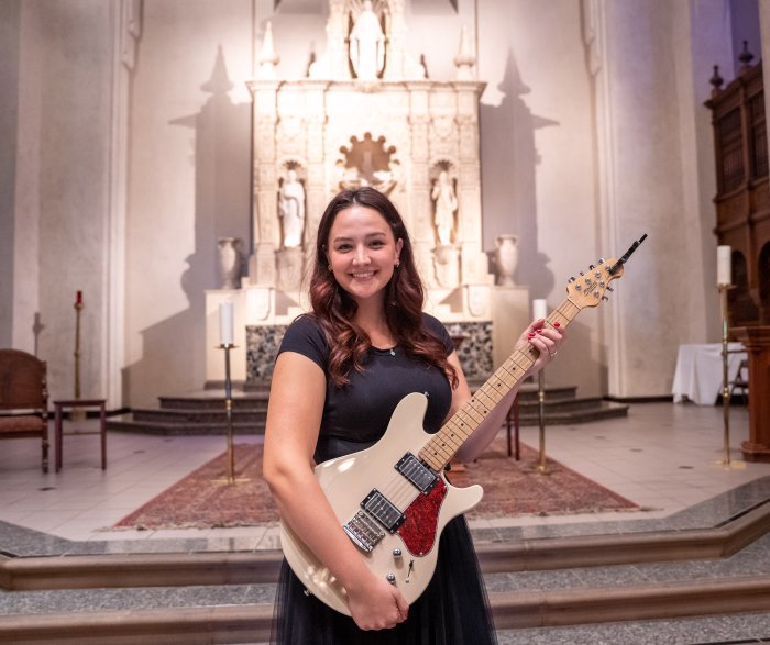 Emily Hancock poses while holding a guitar at SMC Chapel