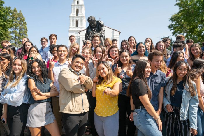 Students in a group smiling in front of the saint mary's college campus