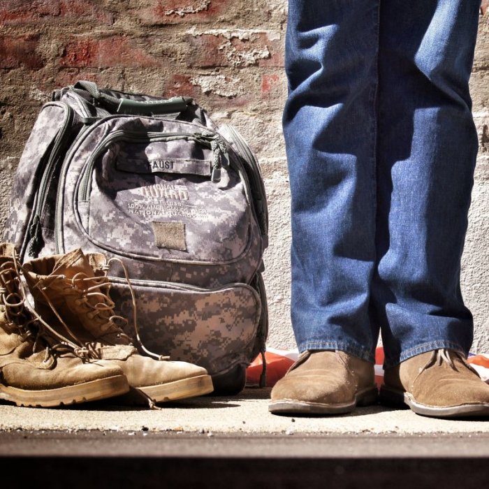 a military veteran standing next to books and backpack