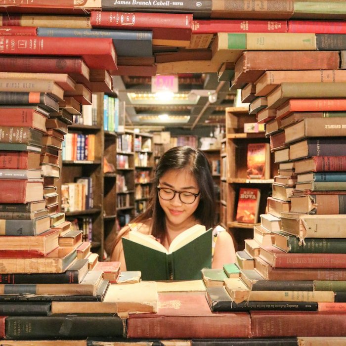 a woman reading a book in a nook made of books