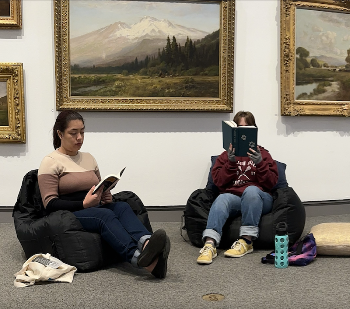 two students reading on beanbags under frame landscape painting