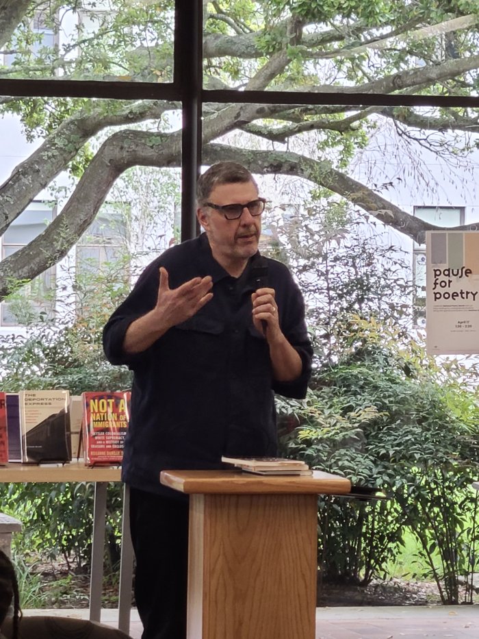 Matthew Zapruder speaking into a microphone and gesturing