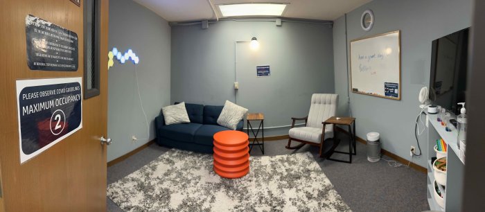 A sensory room with a chairs, couches board and tv