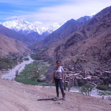woman standing on dirt path with mountains behind