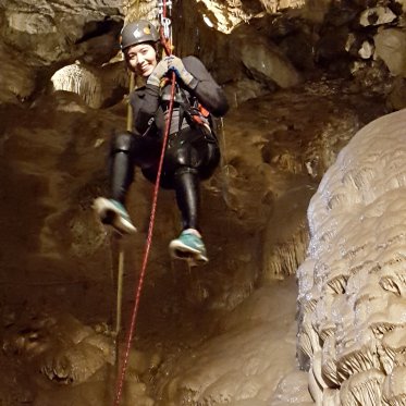 A student in mid-airs smiles while spelunking in Moaning Cavern.