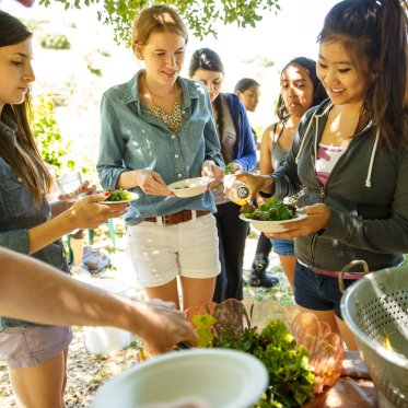 a group of students preparing an outdoor snack/meal from what they harvested in the legacy garden