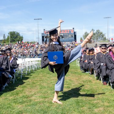 A graduate holding a diploma and doing a dance move