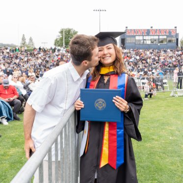 A graduating student being kissed on the cheek