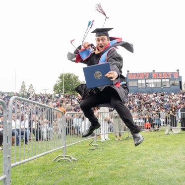 Graduating student jumping holding a diploma