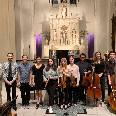 A group photo of chamber musicians posing inside of the chapel