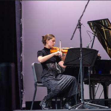 A string instrumentalist performs on stage at LeFevre theatre