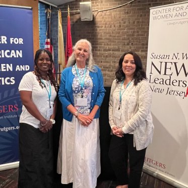 three attendees of CAWP in front of banners