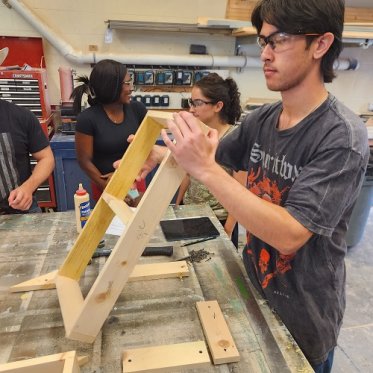 Student building a wooden square for theatre set