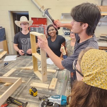 Student hammering a wooden block for theatre set