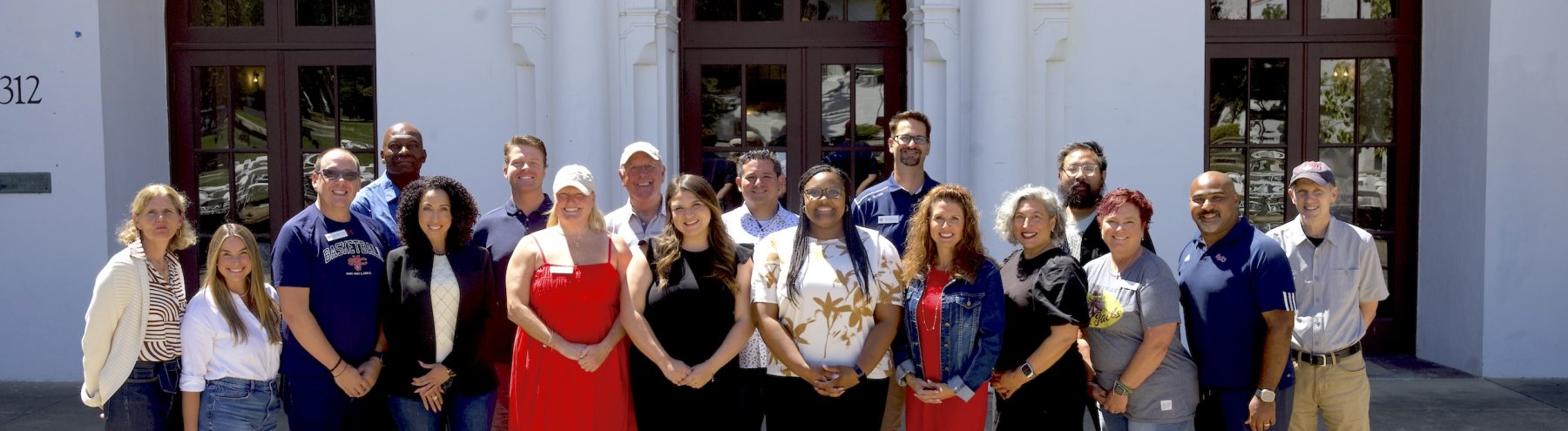 20 adults, the Alumni Board of Directors, smile for a photo