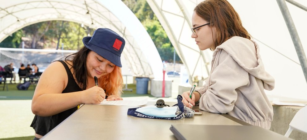 two students are writing in class in the pavilions