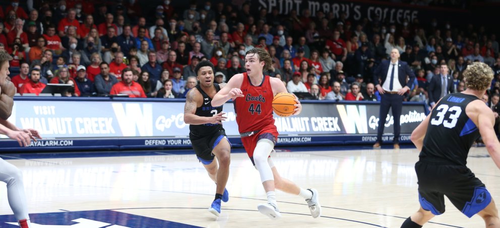 A Saint Mary's basketball player dribbling the ball surrounded by the opposing team. 