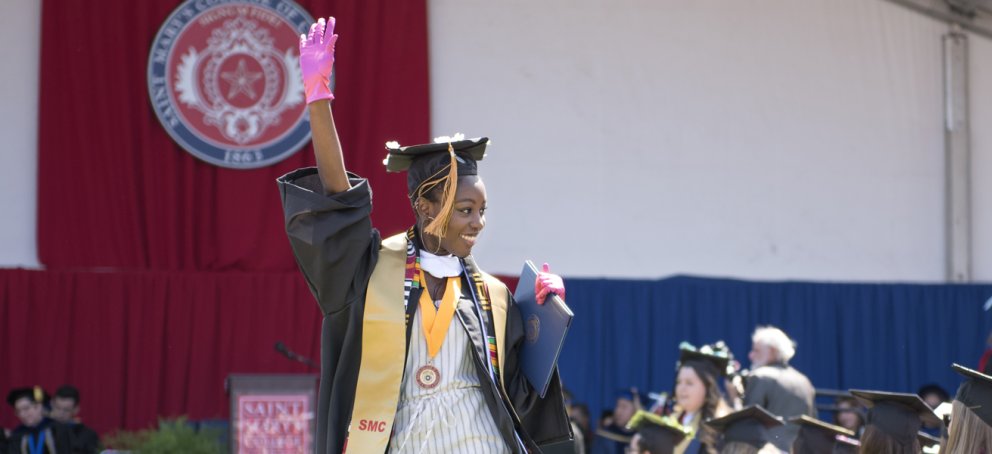 student graduating wearing pink glove and a smile