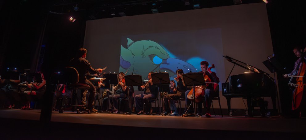 Sixto conducts his band while an animated film is projected in the background of the stage
