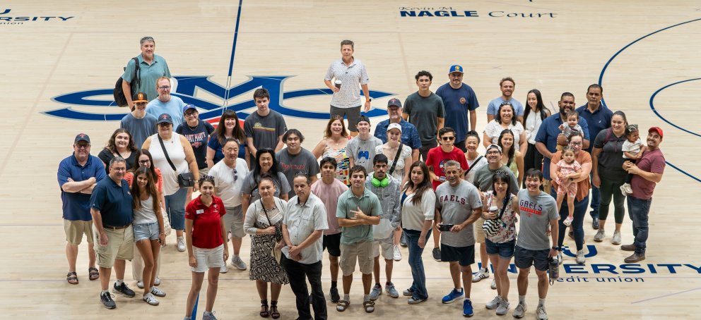30 people stand on the basketball court during a tour of UCU Pavilion.