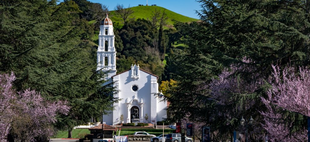 The Chapel stands tall in front of green hills and flowering trees