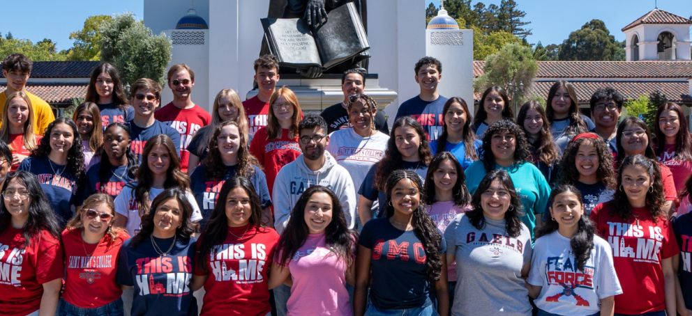 A group of students smiles for a photo in front of a statue, showcasing their camaraderie and school spirit.