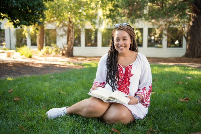 Student sitting on grass with book open