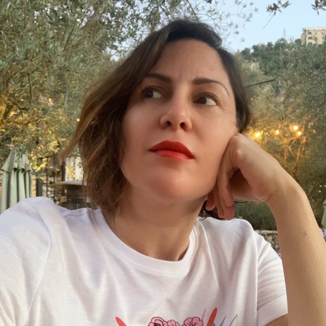 headshot of zeina looking contemplative in front of an outdoor setting