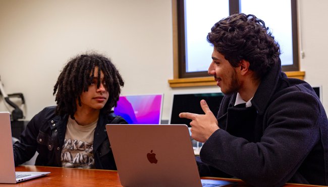 SMC students Jasper Pacheco ’27 and Luis Mora ’27 talking at table with computer for debate practice, 2024