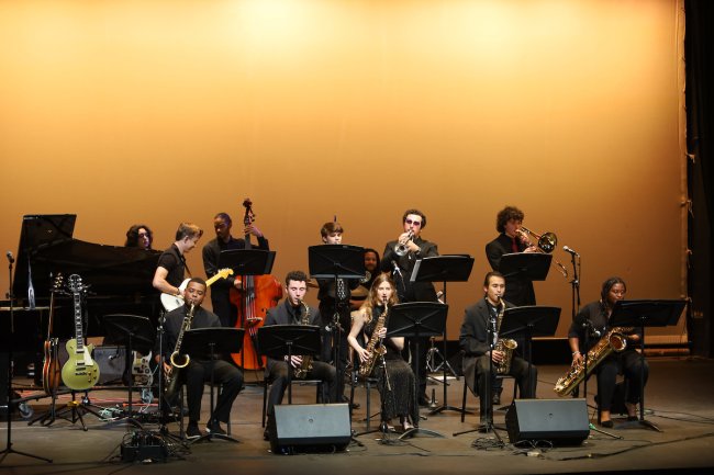 Jazz Band students play multiple instruments on LeFevre stage with a yellow background