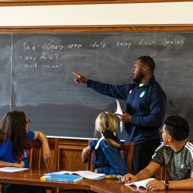 A student teaching other students at a black board