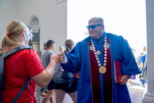 SMC President Roger Thompson fist bumps students at Mass of the Holy Spirit