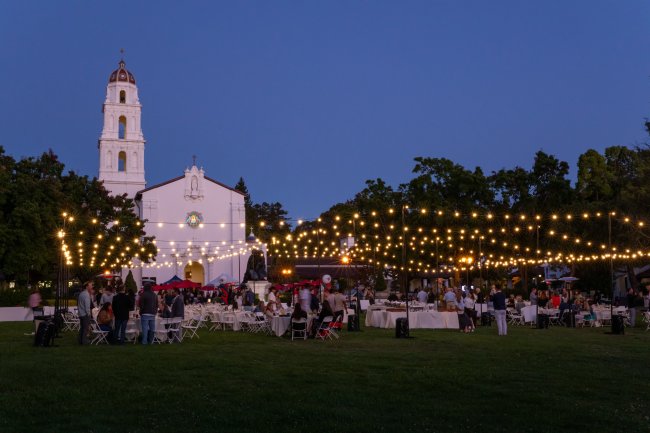 Chapel stands above string lights at twilight
