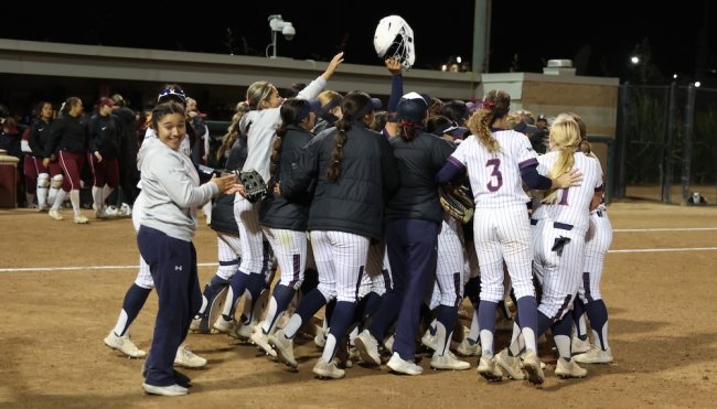 Softball team hugging at home plate after winning WCC title in May 2026