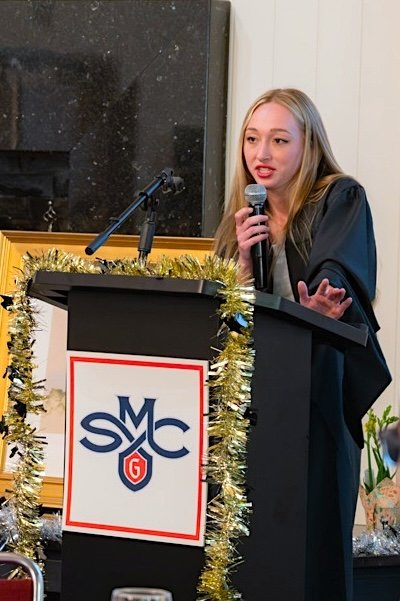 Student McKenna James at podium for Disability &amp; Neurodiversity Graduate Celebration in May 2026