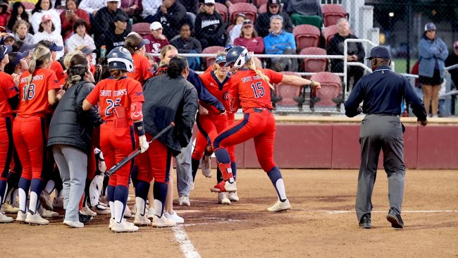 Softball player Sam Buckley touches home while teammates celebrate in May 2026