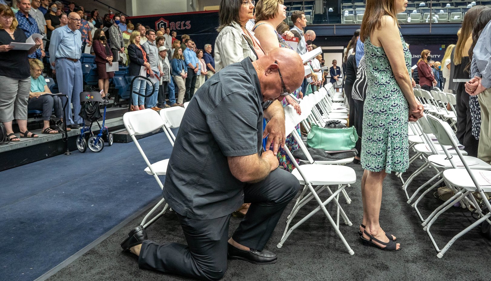 A man kneeling in the commencement liturgy
