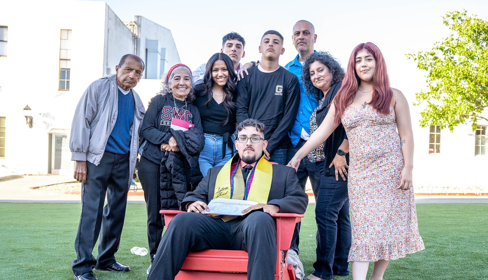 Student sitting on chair and surrounded by his family